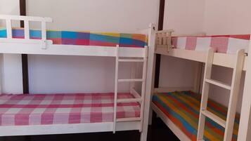 A bunk bed room with a checkered pink and white floor, a colorful striped bedspread, and a white ladder.