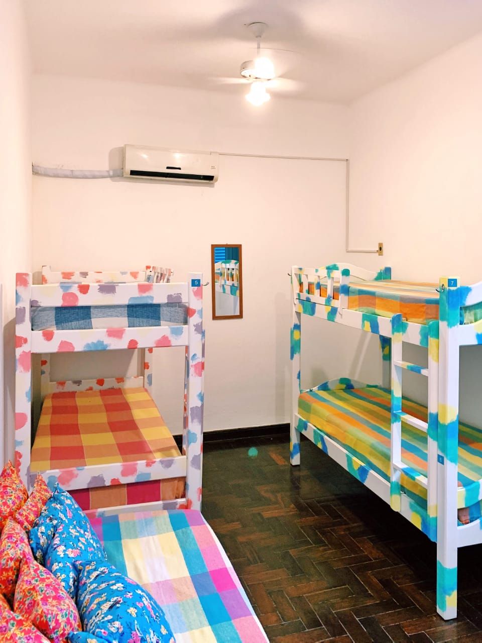 Ein Zimmer mit Etagenbetten, einem Deckenventilator, einer Klimaanlage und einem gerahmten Bild an der Wand.