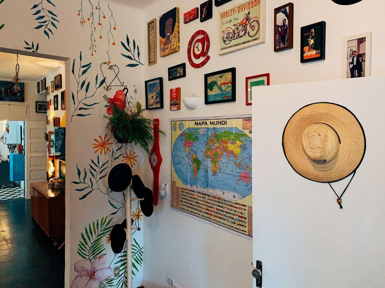 Pared decorada con un mapa del mundo, cuadros enmarcados y un sombrero.