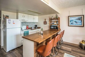 A compact kitchen with a wooden bar area, white cabinets, and a microwave.