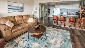A living room with a brown leather sofa, a round coffee table, and a patterned rug.