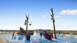 A water play area with a boat-shaped water feature, palm trees, and lounge chairs. - Phoenix V 802 by Liquid Life (Orange Beach)