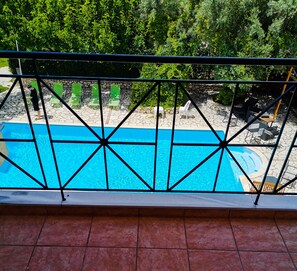 A pool with a clear blue water, surrounded by a stone patio and green chairs. - Calderimi - Lefkada Rooms (Lefkada)