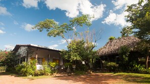 A rural house with a dirt driveway, surrounded by greenery and trees. - Hostel Catavento (Alto Paraíso de Goiás)