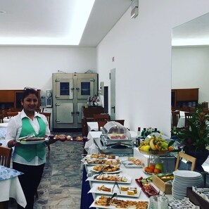 Montaje de bufé con diversos alimentos y un miembro del personal encargado de servir.