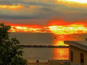 A coastal sunset view with a building in the foreground. - Hotel Dea della Salute (Bellaria-Igea Marina)