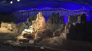 A nativity scene with a statue of Mary and baby Jesus, surrounded by a model town and a cow. - Hotel Dea della Salute (Bellaria-Igea Marina)