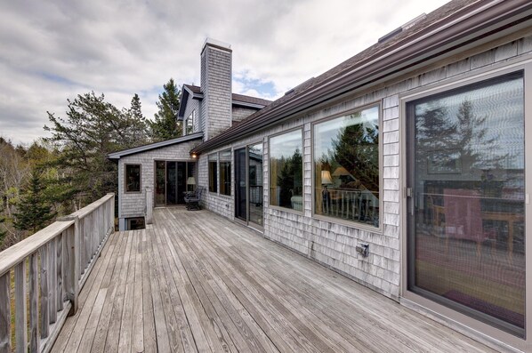 A wooden deck with large sliding glass doors and a chimney.