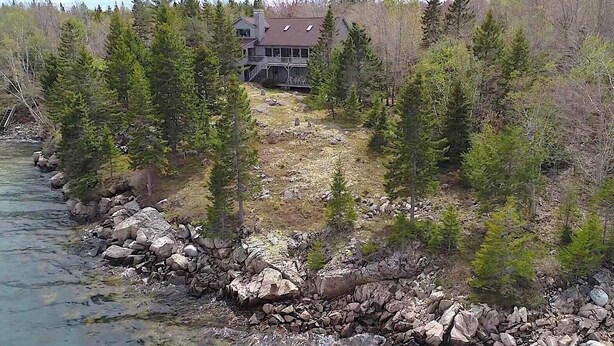 Et lodge med stengrundelse nær en flod, omgivet af tæt skov.