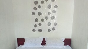 A hotel room with a bed, pillows, and a wall decoration of circular patterns. - Kenangan Guest House (Sabang)