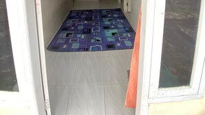 A narrow hallway with a tiled floor, a patterned rug, and a door leading to another room. - Kenangan Guest House (Sabang)