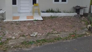 A house with a red roof, a white door, and a small yellow chair outside. - Kenangan Guest House (Sabang)