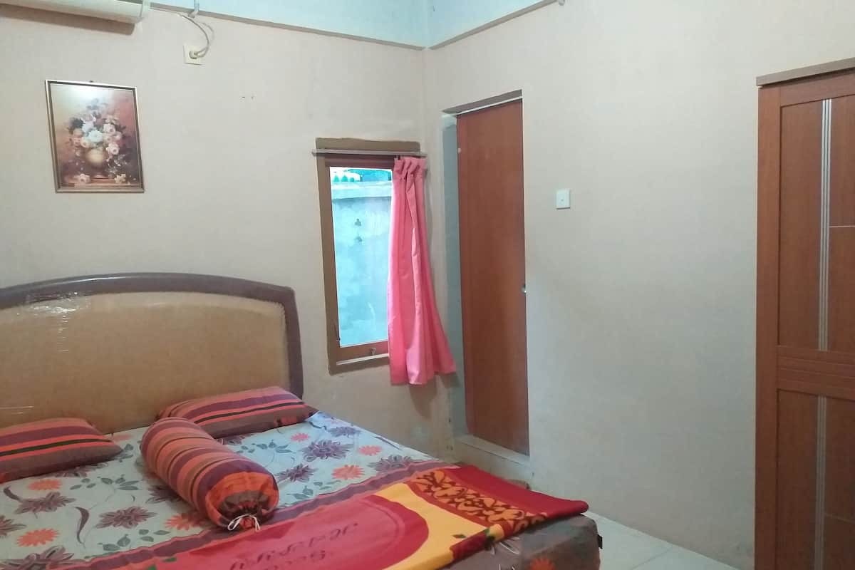 Une chambre à coucher avec un lit, une fenêtre avec des rideaux, une porte et un climatiseur fixé au mur.