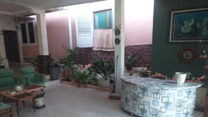 A spacious living area with a tiled floor, a green sofa, a wooden coffee table, and a patterned counter. - Kenangan Guest House (Sabang)