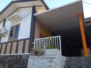 A two-story house with a balcony, a window with a brown frame, and a yellow bicycle decoration. - Kenangan Guest House (Sabang)
