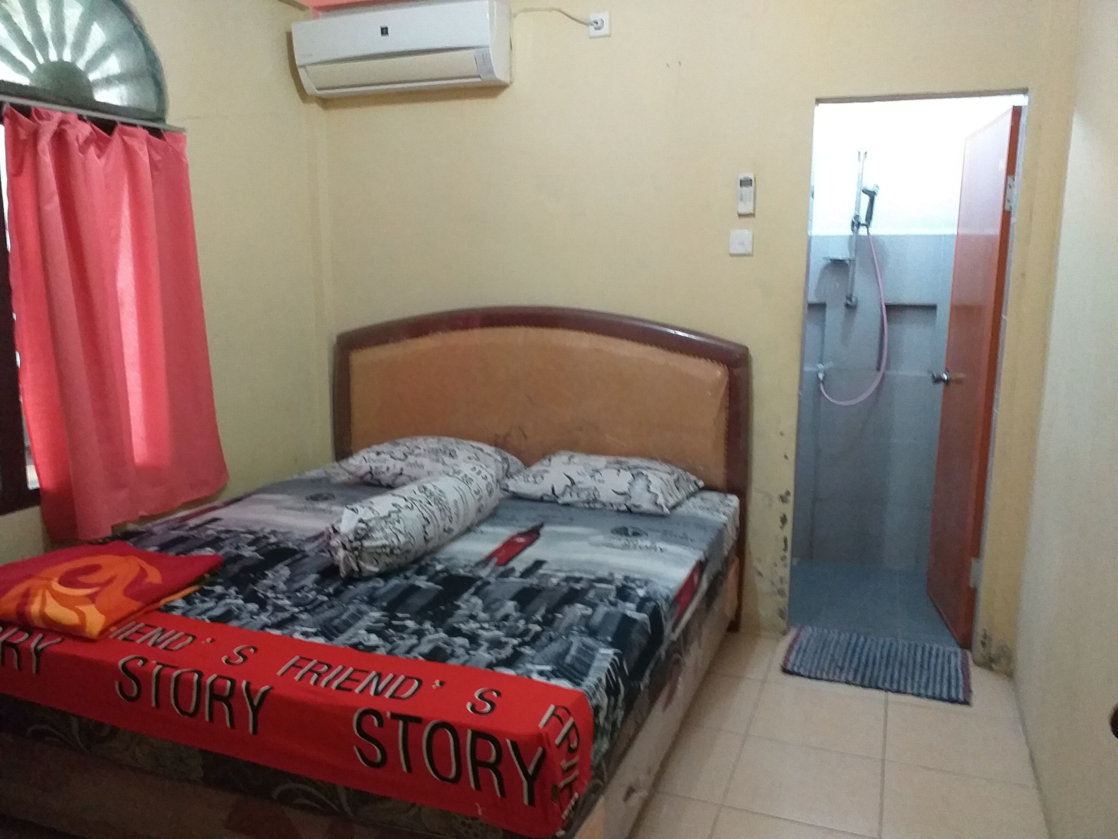 Quarto com cama, chuveiro e ar-condicionado fixado na parede.