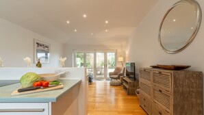 A modern kitchen with a wooden countertop, a dining area with a sofa, and a large mirror on the wall. - This spacious, detached holiday home is just a short walk from the beach. (12 Brecon Close)