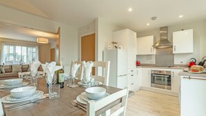 A modern kitchen with white cabinets, a stainless steel range hood, and a built-in oven. - This property is an ideal, and very green choice for your family holiday. (32, Ashton Close)