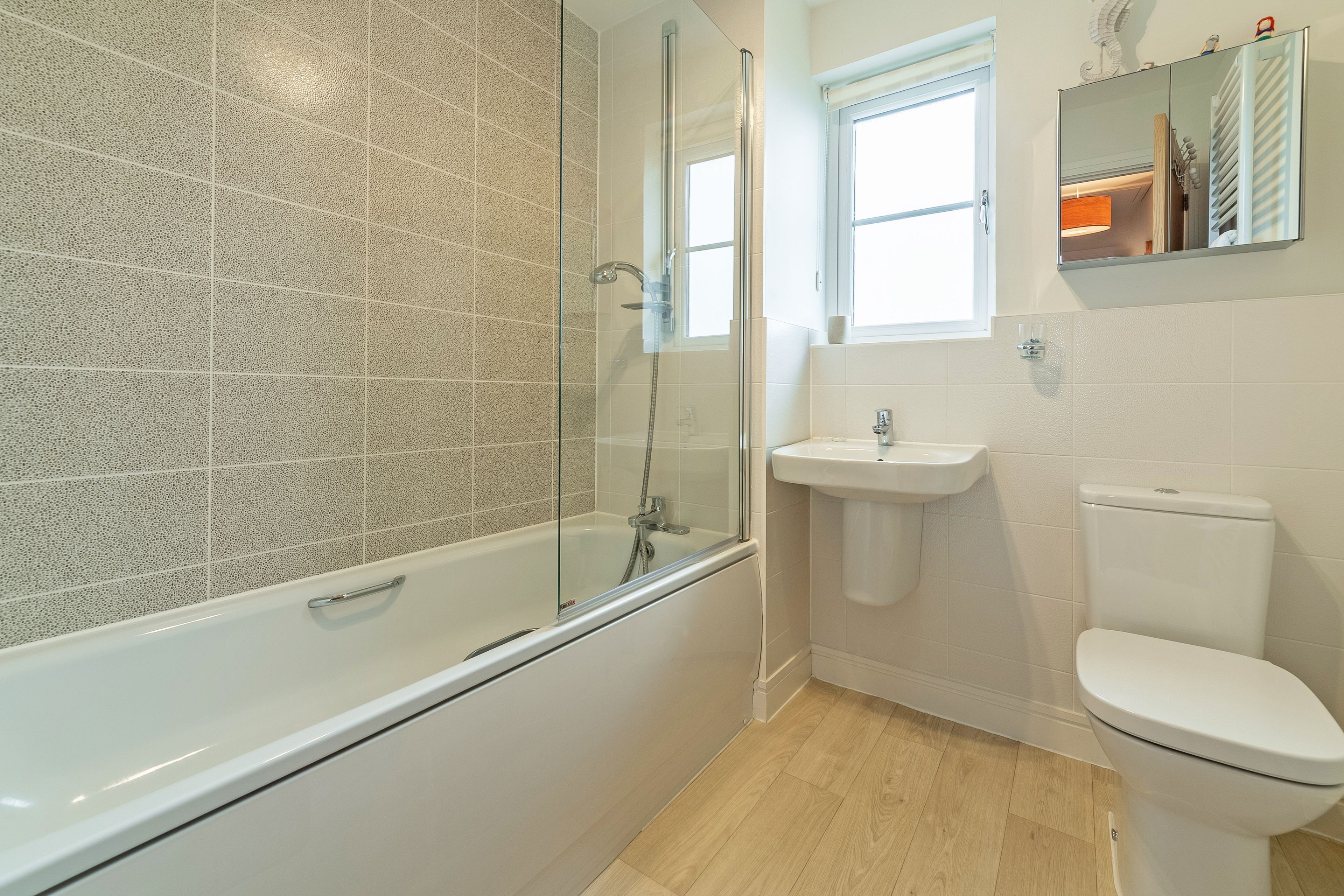 Un bany modern amb dutxa de vidre, un lavabo blanc i un vàter.