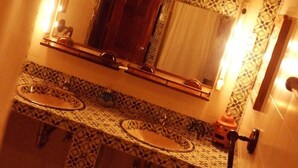 Un baño con salpicadero de azulejos estampados, un espejo grande y dos lavabos.