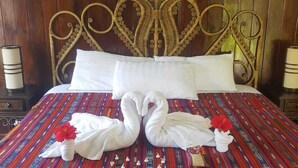 Una cama con cabecera de mimbre, almohadas blancas y una colcha a rayas de colores.