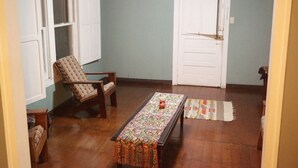 Una habitación con suelo de madera, una mesa con diseño, una silla y una puerta.