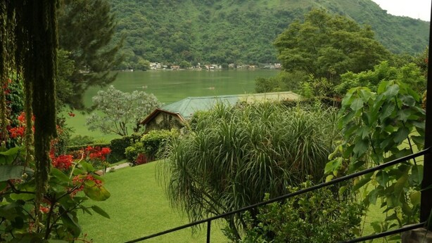Un exuberante jardín con vistas a un lago y colinas.