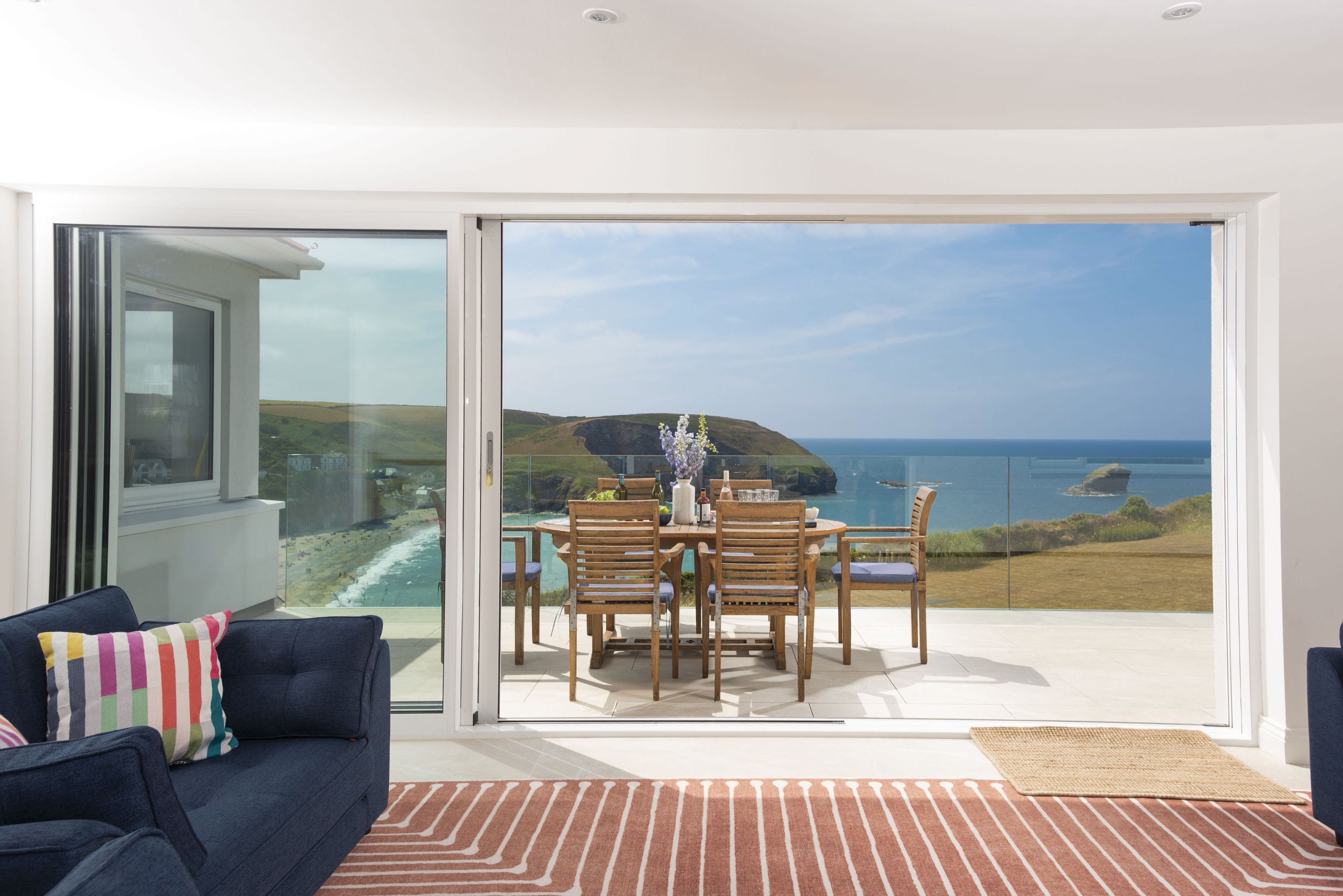 Un salon moderne avec une porte vitrée donnant sur un balcon qui offre une vue sur un paysage côtier.