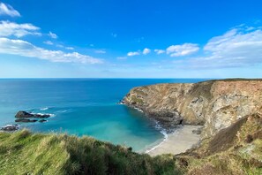 A coastal landscape with a clear sky, a sandy beach, and rocky cliffs. - With uninterrupted sea views, this property enjoys a superb hillside position. (Lighthouse Hill)
