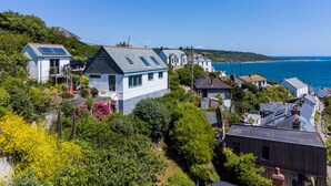 Uma área residencial costeira com casas, um pequeno edifício com painéis solares e vista para o mar.