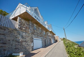 A stone building with a garage, a balcony, and a clear view of the sea. - Superbly appointed accommodation, and a soothing hot tub on the decked balcony. (Battery Hill)