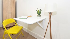 A small workspace with a white desk, a yellow chair, a potted plant, and a floor lamp. - Townhouse @ Earle Street Crewe (Crewe)