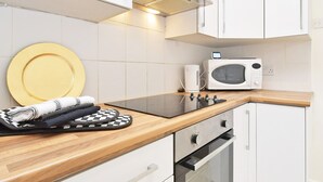 A modern kitchen with white cabinets, a microwave, an oven, and a wooden countertop. - Townhouse @ Earle Street Crewe (Crewe)