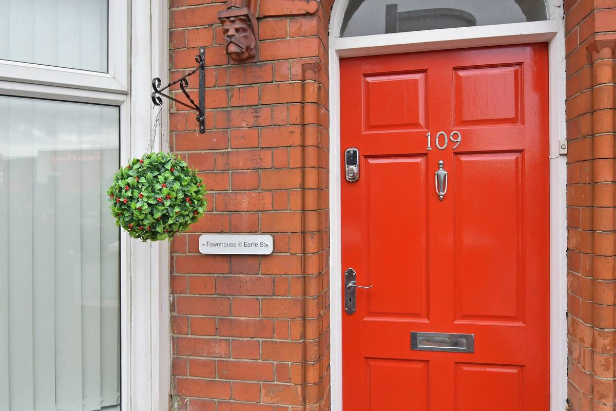 Una puerta roja con el número 109, una planta verde colgante y un letrero que dice 'Townhouse @ Earle St.'