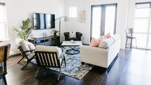 Una sala de estar moderna con un sofá, sillas, una mesa de centro y un televisor.