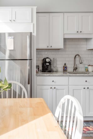 A kitchen with white cabinets, a stainless steel refrigerator, a coffee maker, and a sink. - Bright Charming Guesthouse Close to Downtown DC (Washington)