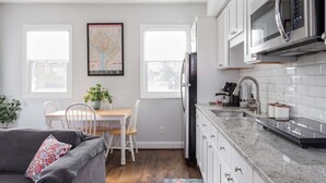 A modern kitchen with white cabinets, a granite countertop, and a stainless steel refrigerator. - Bright Charming Guesthouse Close to Downtown DC (Washington)