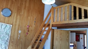A wooden interior with a loft area, a clock, and a map on the wall.
