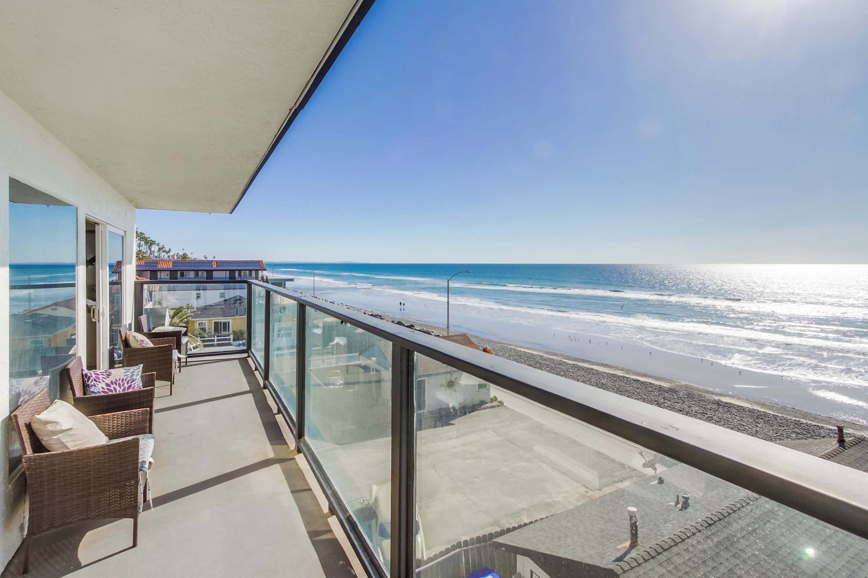 Ein Balkon mit Blick auf den Ozean, Korbmöbel und ein klarer Himmel.