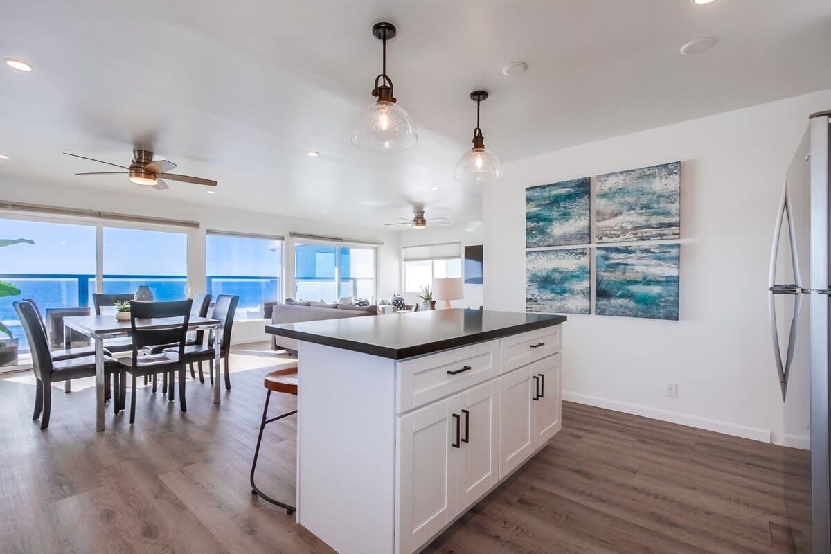 A spacious kitchen with a large island, white cabinetry, and pendant lighting.