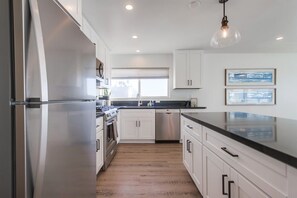 A modern kitchen with stainless steel appliances, white cabinetry, and a black countertop.