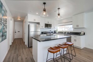 A modern kitchen with white cabinets, stainless steel appliances, and a central island with stools.