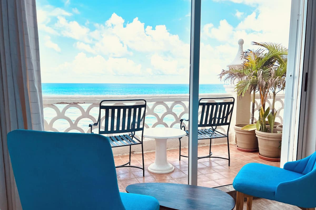 A balcony with two blue chairs, a small round table, and potted plants.