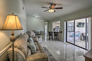 Relax in this spacious living area with a plush sofa, floor lamp, and ceiling fan, perfect for unwinding after a day out.