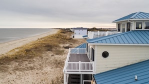 Una propiedad frente a la playa con un edificio blanco de techo azul, un balcón y una pequeña terraza.
