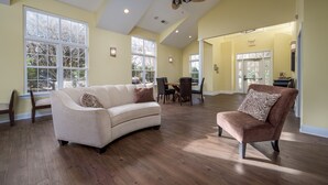 A spacious living room with a high ceiling, large windows, and hardwood flooring. - BIKE TO REHOBOTH & LEWES BEACHES & RESTAURANTS, 19781 Keystone Dr., Rehoboth (Rehoboth Beach)