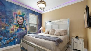 Ein Schlafzimmer mit einem Bett, einem Nachttisch, einem Wand-Fernseher und einem Deckenventilator.