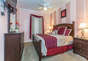 A bedroom with a bed, a dresser, a nightstand, a ceiling fan, and a window with curtains. - Windsor_palms_102 (Kissimmee)