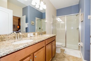 Une salle de bain avec un meuble-lavabo à deux vasques, une douche à parois de verre et des toilettes.