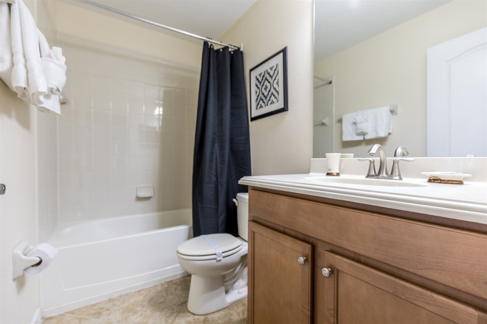 A bathroom with a bathtub, toilet, and vanity with a mirror.